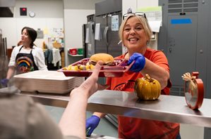 School food service employee serves lunch.