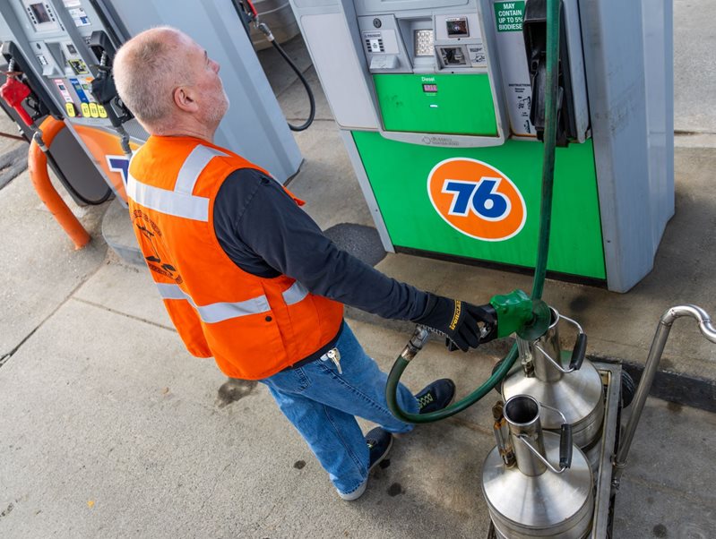 man filling canister with fuel while looking at pump