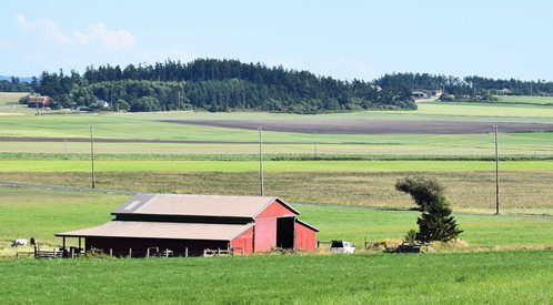Photo of a farming landscape with a red barn in the foreground