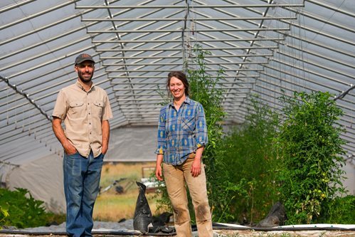 Two farmers standing in front of hoop house.