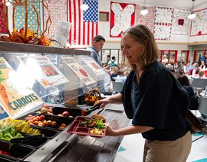 Woman loading tray for school lunch.