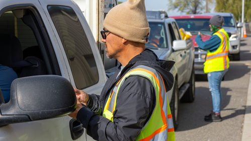 man and woman talking to people in pickup trucks