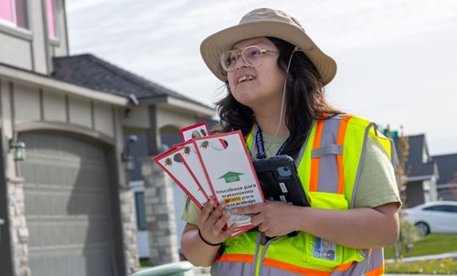 Woman wearing safety vest smiling and holding outreach materials