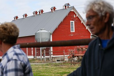 Farmers with red barn in background.